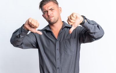 unpleased blonde handsome man thumbing down isolated white wall with copy space