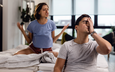 young man feeling stressed out having headache while his girlfriend is arguing with him bedroom