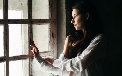 Mulher pensativa olhando pela janela representando relacionamento abusivo, conflito emocional e sensação de prisão psicológica